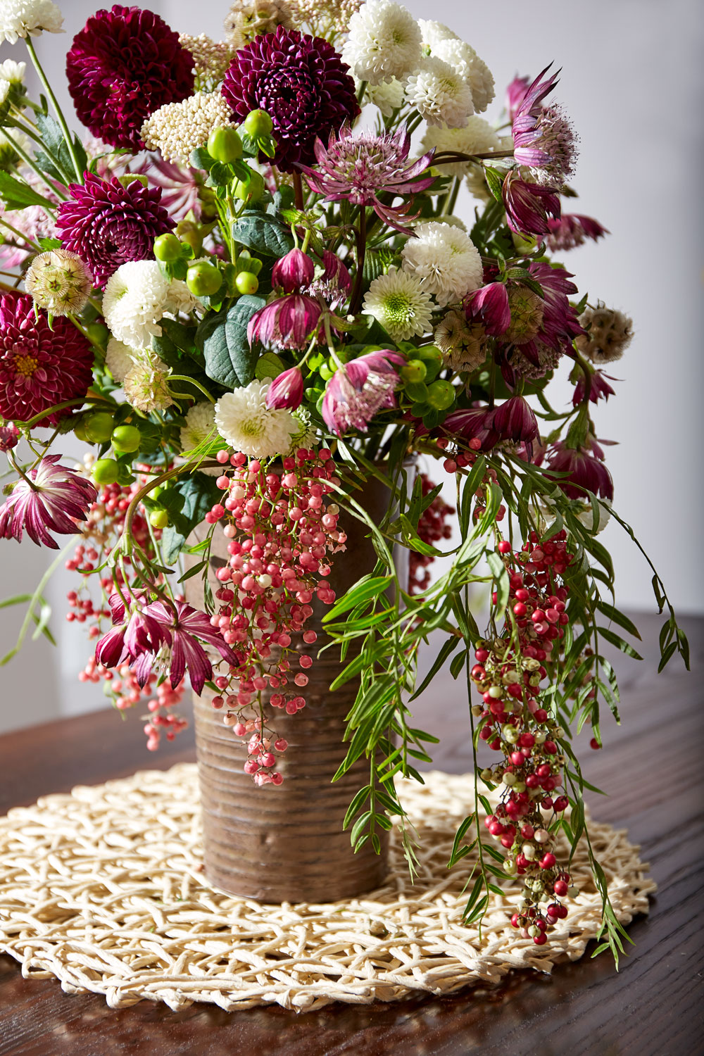 Dahlias peppercorns and flowers in a bucket on a table