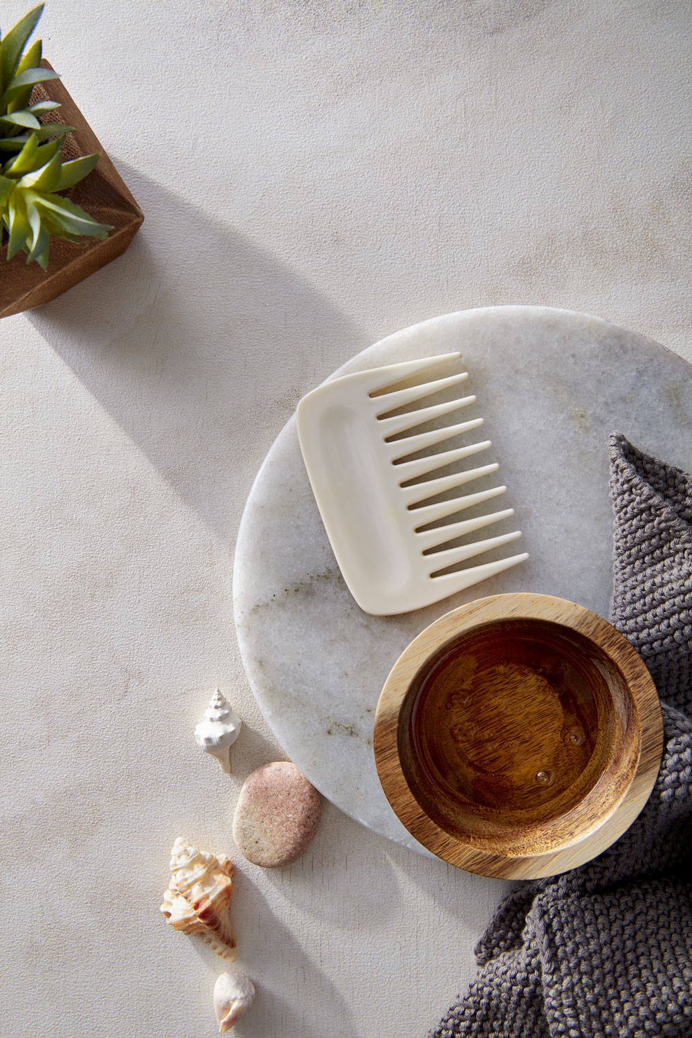 Hair oil in small wooden vessel with comb