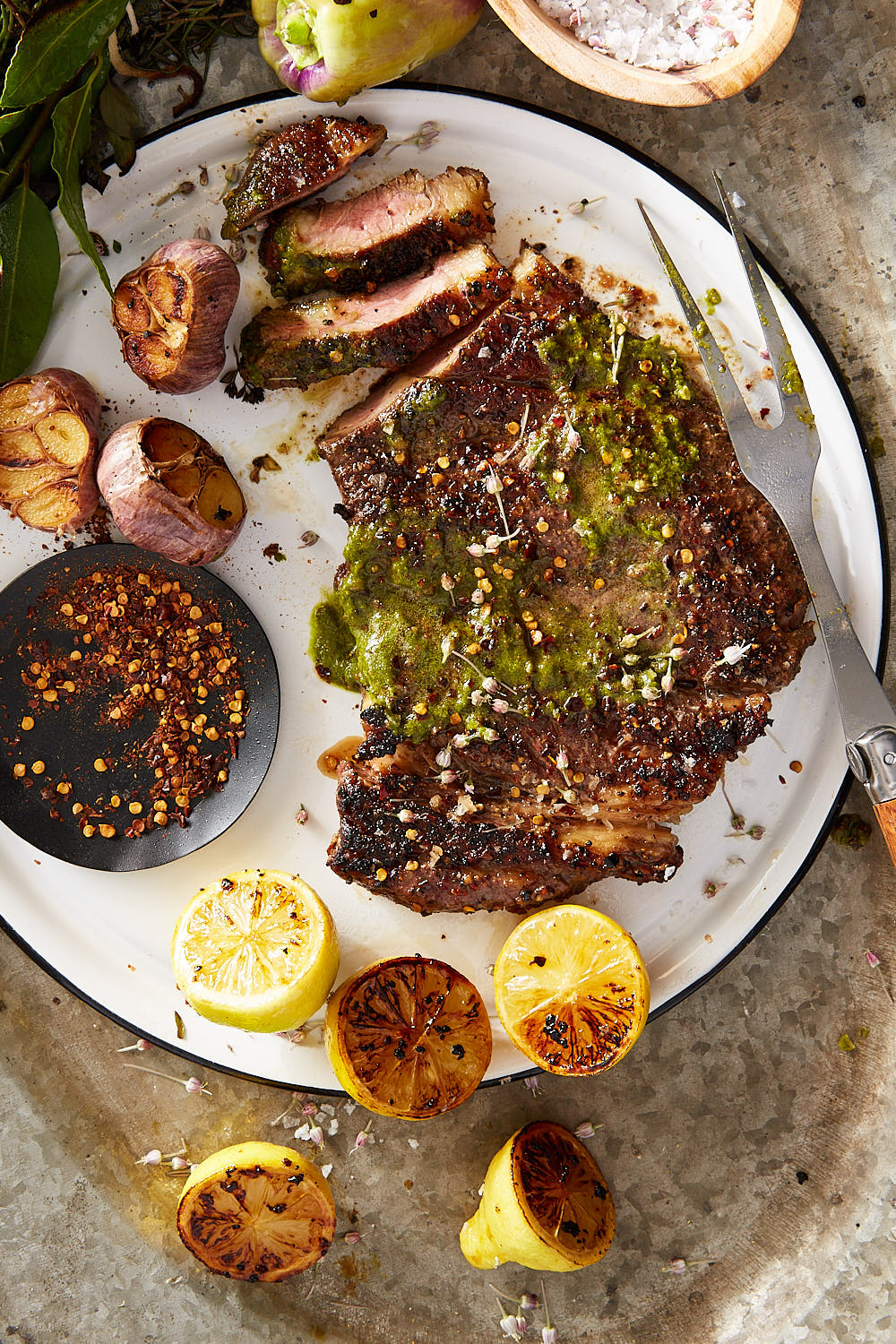 Grilled steak on a white plate with lemons